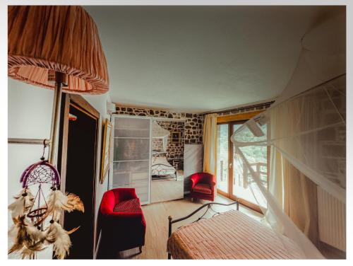 a room with a bed and two red chairs in it at Fairytale Stone House in Karpenisi