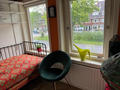 a bedroom with a bed and a chair and a window at BeBaBops Homestay Utrecht in Utrecht