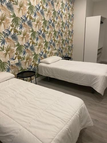 two beds in a hotel room with a wallpaper at Apartamentos Kai Santurtzi in Santurce