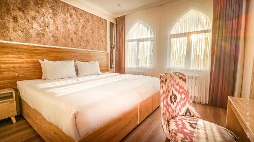 a bedroom with a bed and a chair in it at Hotel Bankir Khiva in Khiva