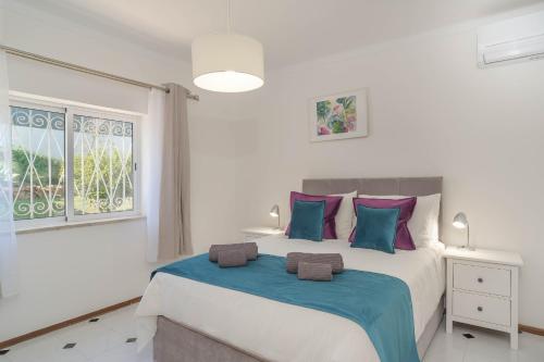 um quarto com uma cama grande com almofadas azuis e roxas em Casa SP- Villa with heated pool near Vilamoura, Vale do Lobo em Quarteira