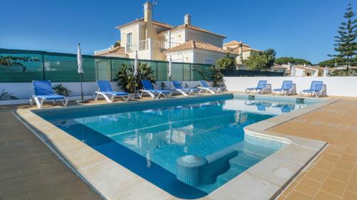a swimming pool with chairs and a house in the background at Casa SP- Villa with heated pool near Vilamoura, Vale do Lobo in Quarteira