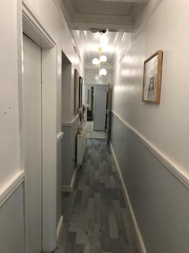 a hallway with white walls and a long hallway with a painting at Rose Cottage in Tipton