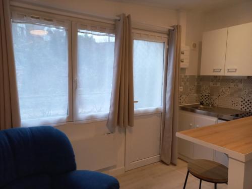 uma cozinha com duas janelas grandes e uma mesa em Studio tt confort neuf et équipé em Noyon