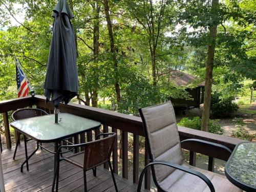 une table et des chaises avec un parasol sur une terrasse dans l'établissement Round Cabin - 5 Min to Bedford PA - Deck - Hike- Golf, à Bedford