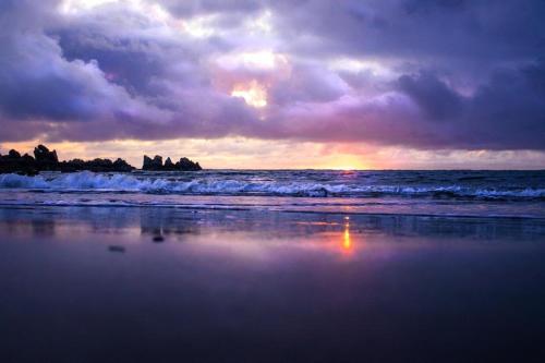 a sunset on a beach with the ocean at Lighthouse Farm in Greencastle