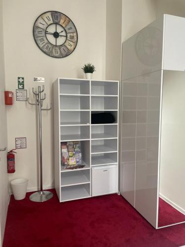 a white book shelf with a clock on the wall at DATRI Petite Suite 4 in Vienna