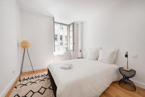 une chambre blanche avec un lit blanc et une fenêtre dans l'établissement Les Colonnes - T3 - Bastide, à Carcassonne