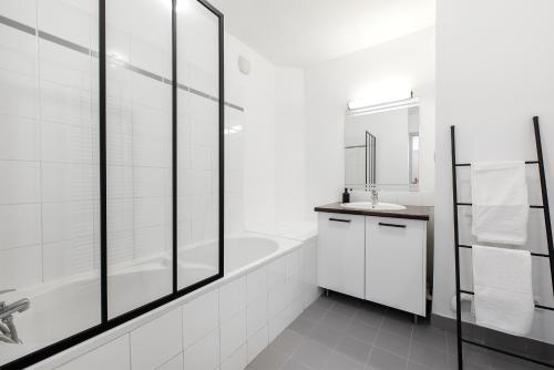 une salle de bain blanche avec une baignoire et un lavabo dans l'établissement Les Colonnes - T3 - Bastide, à Carcassonne