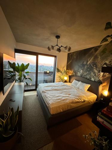 a bedroom with a bed and a large window at Skyline elegance with free parking in Bratislava