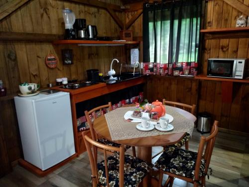 a kitchen with a wooden table and a table and chairs at Encosta Dos Pinheiros in Gramado