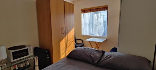 Schlafzimmer mit einem Bett, einer Mikrowelle und einem Fenster in der Unterkunft Wembley house in London