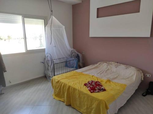 um quarto com uma cama com um cobertor amarelo em maison spacieuse et lumineuse em Hammamet Sud