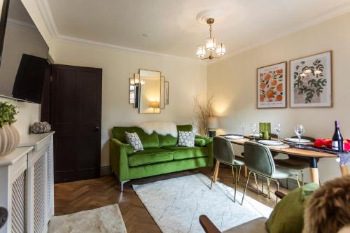 a living room with a green couch and a table at Luxe Stratford Townhouse beautifully renovated, free parking sleeps 4, 2 bathrooms, minutes walk to town, RSC - pet friendly in Stratford-upon-Avon