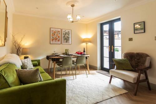 a living room with a green couch and a table at Luxe Stratford Townhouse beautifully renovated, free parking sleeps 4, 2 bathrooms, minutes walk to town, RSC - pet friendly in Stratford-upon-Avon