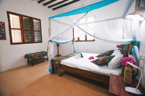 a bedroom with a bed with a canopy at Cozy Lodge - Guesthouse in Jambiani