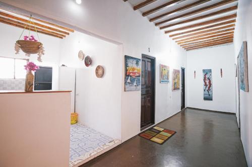 a room with white walls and a hallway with paintings at Cozy Lodge - Guesthouse in Jambiani