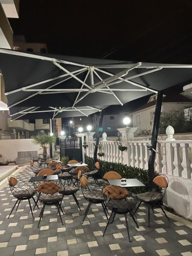 a group of tables and chairs under an umbrella at Hotel Vila Dedej in Durrës