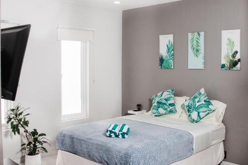 a bedroom with a bed with blue and green pillows at Flora Fauna 84 Aruba Apartment in Palm-Eagle Beach