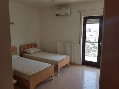 two beds in a room with a window and a door at Residence Artemide 5° in Isernia