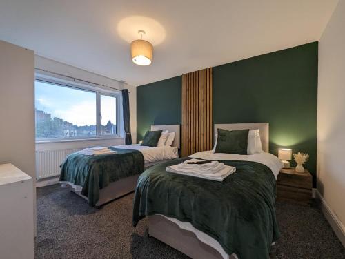 a bedroom with two beds with green walls and a window at Oakwood Suite - Sleeps 5 - Contractors - Smart TVs in all rooms in Cheshunt