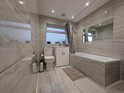 a bathroom with a tub and a toilet and a sink at Oakwood Suite - Sleeps 5 - Contractors - Smart TVs in all rooms in Cheshunt