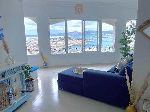 uma sala de estar com um sofá azul e janelas em Dar Lahlou em Tânger