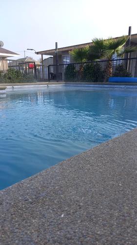 的住宿－Cabañas Rancho Carmelitas, Pullally, localidad agrícola de Papudo，一座拥有蓝色海水和棕榈树的游泳池