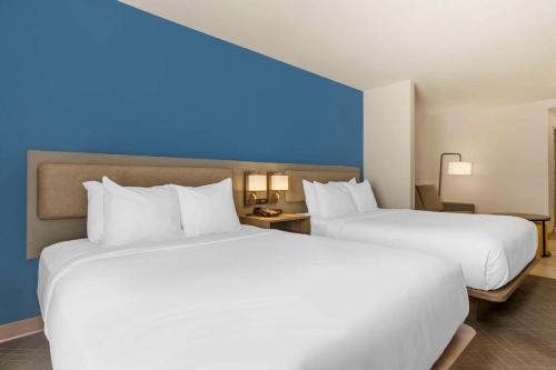 two beds in a hotel room with white sheets at Comfort Suites Columbia Northeast - Fort Jackson in Columbia