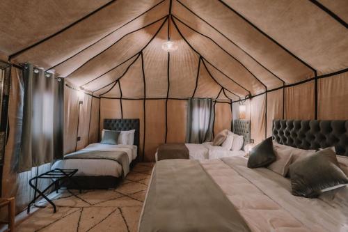 a room with two beds in a tent at desert camp in Adrouine