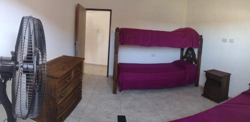 a bedroom with a bed with purple sheets and a dresser at Complejo Bru-Mar in Los Olivares