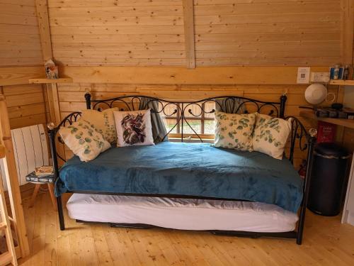 a bedroom with a bed with blue sheets and pillows at Woods Meadow Glamping in West Malling