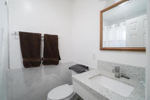 a white bathroom with a sink and a mirror at SIGNAL HILL MOTEL BEACH MOTEL in Long Beach