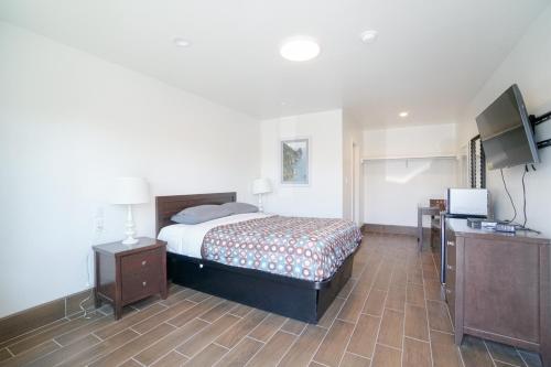 a bedroom with a bed and a flat screen tv at SIGNAL HILL MOTEL BEACH MOTEL in Long Beach