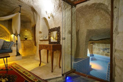 a room with a fireplace and a table with a mirror at Cappadocia Nar Cave House & Swimming Pool in Nevsehir