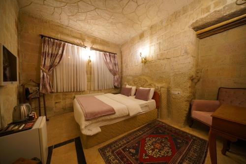 a small bedroom with a bed and a window at Cappadocia Nar Cave House & Swimming Pool in Nevsehir