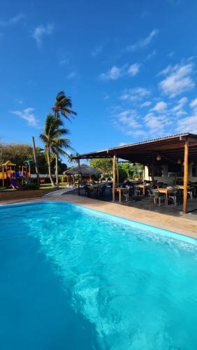 una gran piscina azul junto a un restaurante en Pousada Vila Cajuína - Luís Correia en Luis Correia