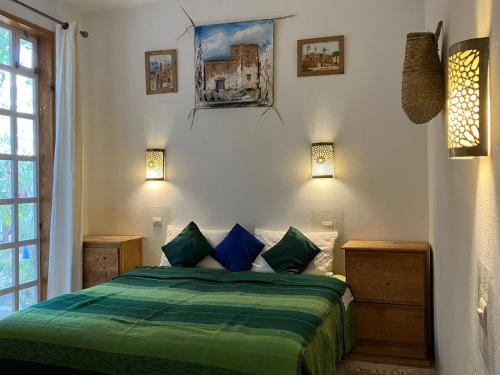 a bedroom with a green bed with two blue pillows at Paradise Guest House in Agadir