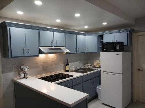 a kitchen with blue cabinets and a white refrigerator at Bonito Departamento Confortable in Tijuana