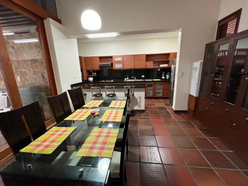 eine Küche mit einem langen Tisch mit Stühlen und einer Küche mit einem Kühlschrank und einem Wasserkocher in der Unterkunft Cómoda Habitación Privada - Ciudad Jardín in Cali