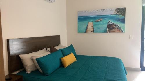 een slaapkamer met een groen bed en een schilderij aan de muur bij Condo 204 in Resort Community Grand Sirenis in Akumal