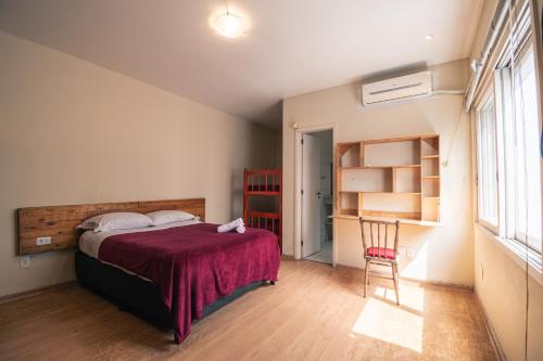 a bedroom with a bed and a chair and a window at Pelotas Bier Hostel in Pelotas