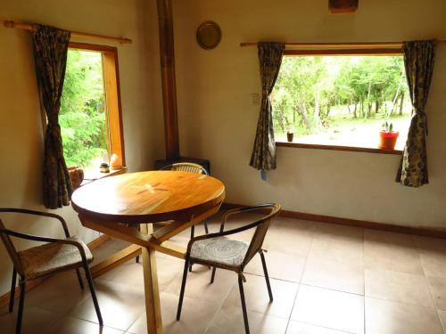una mesa de madera y sillas en una habitación con ventana en Hermosa casa rodeada de bosque en Los Repollos