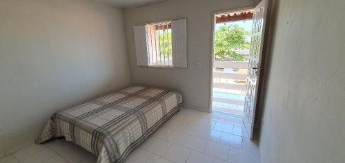 a small bedroom with a bed and a window at Vila Mar Flats - 1 Dorm - Guriri - 800m da Praia in São Mateus