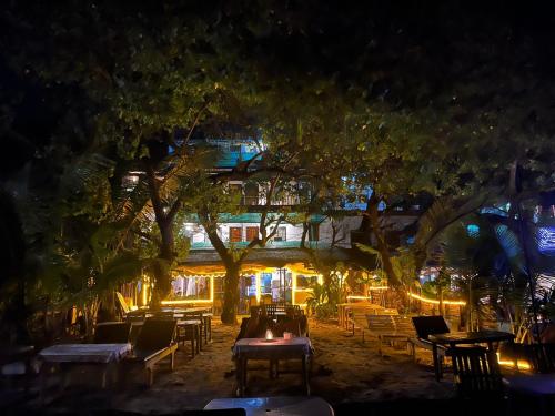 アランボールにあるHAKUNA MATATA - Best budget stay at Arambol Beach, Goaのテーブルと椅子が備わるレストランの夜景を望めます。