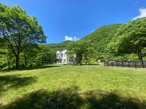 a house in the middle of a field with a hill at 軽井沢ICから3分/立地抜群/おしゃれなフィンランドログハウス in Karuizawa