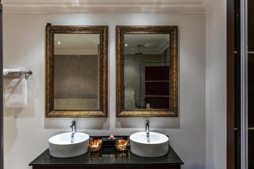 two sinks in a bathroom with two mirrors at Protea Hotel by Marriott Lagos Kuramo Waters in Lagos