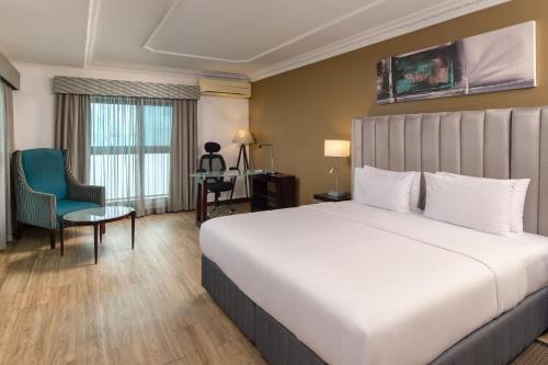 a hotel room with a large bed and a chair at Protea Hotel by Marriott Lagos Kuramo Waters in Lagos