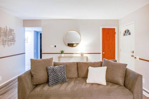 a living room with a brown couch and a mirror at Modern Cozy Home 4 min Drive from Notre Dame in South Bend