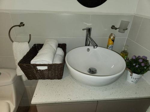 - Baño con lavabo y cesta de toallas en Bonito Apartamento en zona exclusiva y tranquila, en Quetzaltenango